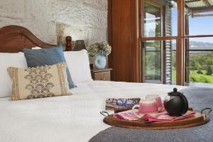 a tray with a tea set on a bed at Christophers Cottage in Bilpin