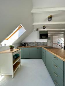 an attic kitchen with green cabinets and a staircase at Windhouse in Jastarnia