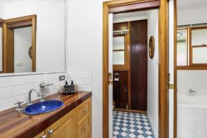 a bathroom with a blue sink and a tub at Christophers Cottage in Bilpin