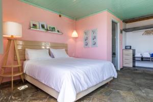 a bedroom with a white bed and pink walls at Panormos Beach Hotel Skopelos in Panormos Skopelos