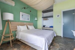 a bedroom with a white bed and green walls at Panormos Beach Hotel Skopelos in Panormos Skopelos