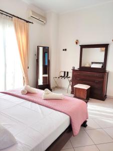 sypialnia z łóżkiem z różowym kocem i lustrem w obiekcie Anastasiou Home in central crossroad w mieście Perdika