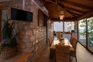 a dining room with a table and a tv on a stone wall at Sun gardens in Šibenik