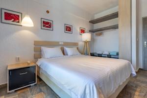 a bedroom with a white bed and a tv at Panormos Beach Hotel Skopelos in Panormos Skopelos