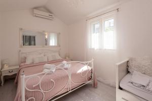 a white bedroom with a pink bed and a mirror at Sun gardens in Šibenik +72 photos