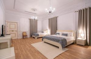 a large white bedroom with two beds and a chandelier at Vila Ferdinand Modern Rooms In Tirana's Center in Tirana