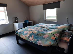 een slaapkamer met een bed met een kleurrijk dekbed bij 't Brugske in Deurne