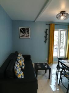 a living room with a black couch and a table at Promotion du Jour - Le Figuier in Deuil-la-Barre