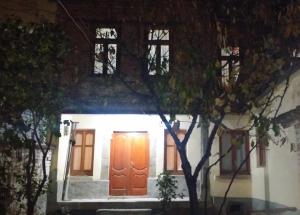 uma casa com uma porta laranja à noite em Vila 1926 Hostel em Korçë