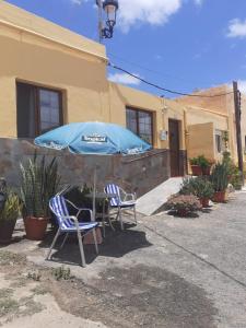 two chairs and an umbrella in front of a house at La Vega R. in Vega de Río de Palmas