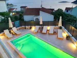 a swimming pool with chairs and a table at Vacation house with heated swimming pool 70 meters from the beach-Bobanac in Ražanj +76 photos