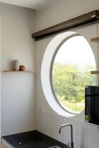 una cocina con una ventana redonda sobre un fregadero en Natsu No Hanabi Villa & Apartment, en Da Nang