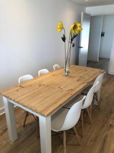 een houten tafel met witte stoelen en een vaas met bloemen bij The Towan Lookout in Newquay