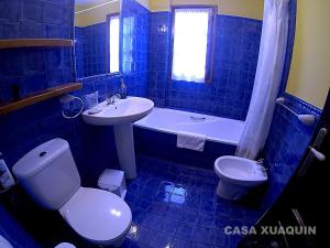 a blue tiled bathroom with a toilet and a sink at Casa Xuaquin in Moal