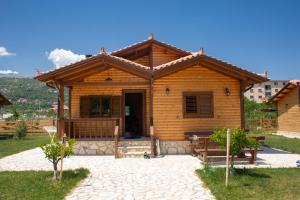 uma cabana de madeira com um alpendre e uma porta em Sancho Farm Albania em Memaliaj