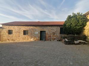 a stone building with a door and a tree at Refúgio do Côa - Pure Countryside Experience in Pinhel