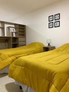 two beds in a room with yellow sheets at Happy Guest Apart 50 in Ushuaia