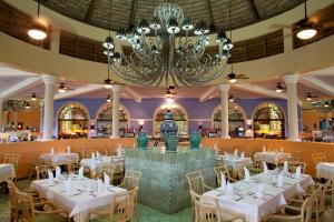a banquet hall with white tables and chairs and a chandelier at Iberostar Costa Dorada in San Felipe de Puerto Plata