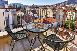 a table with two chairs and a tray of donuts on a balcony at Arvala Lux Apartments in Budva