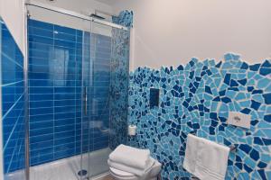 a blue tiled bathroom with a shower and a toilet at A' Treglia B&B in Santa Maria di Castellabate