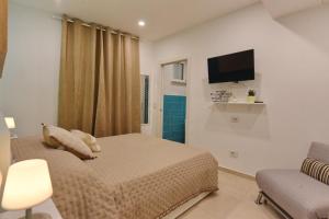 a bedroom with a bed and a tv and a chair at A' Treglia B&B in Santa Maria di Castellabate