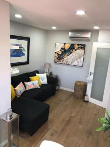 a living room with a black couch and wooden floors at Praia da Rocha - Charming Guest House in Portimão