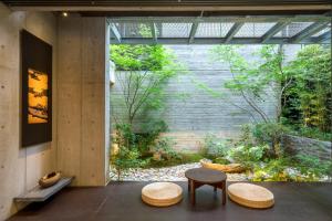 a room with two tables and two stools in front of a garden at Genji Kyoto, a Member of Design Hotels in Gionmachi