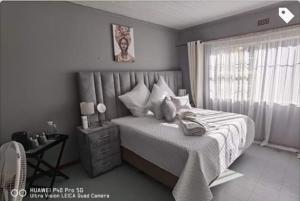 a bedroom with a bed and a table and a window at 016 Guest House in Vanderbijlpark