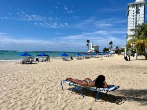 a woman laying on a beach chair on the beach at Private Apartment at Maré St Clair Hotel in San Juan
