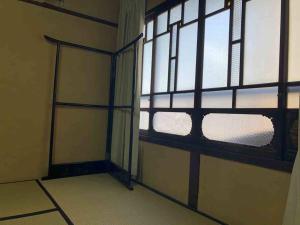 越中城端　荒町庵 في Nanto: غرفه فاضيه فيها باب ونافذه