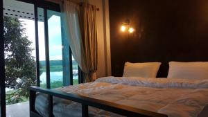 a bedroom with two beds and a large window at บาย เดอะแดม คาเฟ่ แอนด์ ฟาร์มสเตย์ By the dam Cafe and Farmstay in Plai Phraya
