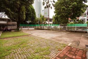an empty parking lot with a fence and trees at Casa Heradurra Uno/Dos in Manila