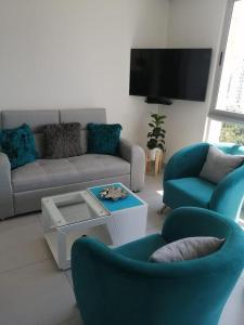 a living room with a couch and chairs and a tv at Apartamento - Velas al Mar, Santa Marta in Gaira