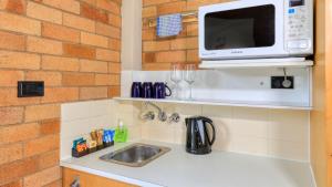 a kitchen counter with a sink and a microwave at Court Street Motel in Parkes