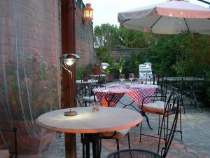 un patio con mesas, sillas y una sombrilla en Locanda La Pieve, en Semproniano