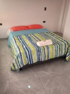 uma cama com um edredão listrado colorido num quarto em CASA TOÑITA em Oiba