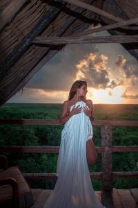 Una donna con un vestito bianco in piedi di fronte a una recinzione di Hidden Treehouse Tulum Eco-Hotel a Tulum