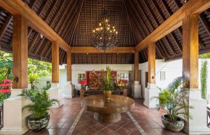 un grand hall avec une table et des plantes en pot dans l'établissement Villa Kayu Raja, à Seminyak