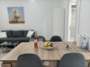 einen Holztisch mit einer Schale mit Obst und Weingläsern in der Unterkunft City Aurora in Athen