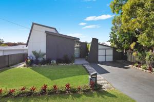 a house with a garden in front of it at MOOLOOLABA CANAL HOME - Modern 4Bedroom with Spa, Sauna and Private Pontoon - NEW proprietor 2024 in Mooloolaba