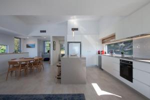 クーラムビーチにあるCoolum Beach Holiday Houseのキッチン(白いキャビネット付)、ダイニングルーム(テーブル付)