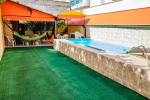 卡波布里奧的住宿－Casa De Praia Sol e Mar，一个带绿色地板和遮阳伞的游泳池