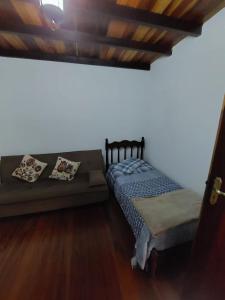 een slaapkamer met een bed en een bank bij Chalé Encantado in Campos do Jordão