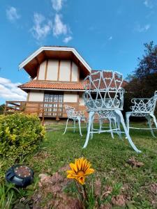 een tuin met twee stoelen en een tafel en een huis bij Chalé Encantado in Campos do Jordão