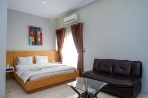 a bedroom with a bed and a chair and a window at Sans Hotel Absari Yogyakarta in Durenan