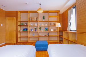 a bedroom with two beds and a book shelf at Naha Gajumaru Apartment Hotel 401 in Naha