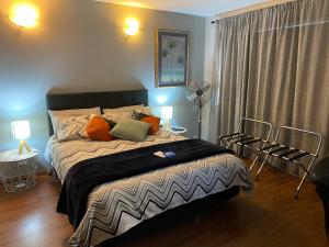 a bedroom with a large bed and a fan at Opanuku Out West in Auckland