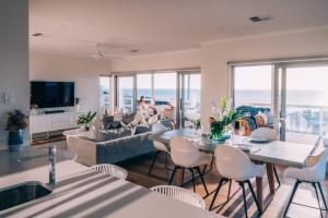 Una sala de estar con un sofá, una mesa y sillas. en ōSHEN - Sleeps12 Gym Kayak MountnBike BeachFrnt, en Aldinga Beach