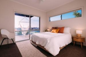 Un dormitorio con una cama y una ventana grande. en ōSHEN - Sleeps12 Gym Kayak MountnBike BeachFrnt, en Aldinga Beach