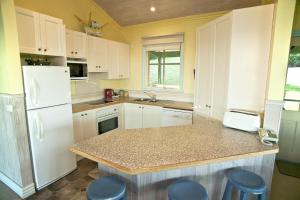 a kitchen with white cabinets and a white refrigerator at Bennetts Beach House in Apollo Bay